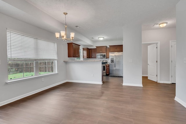 kitchen featuring appliances with stainless steel finishes, dark hardwood / wood-style flooring, decorative light fixtures, and an inviting chandelier