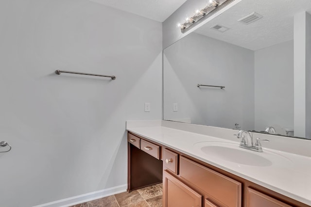 bathroom featuring vanity, a textured ceiling, and toilet