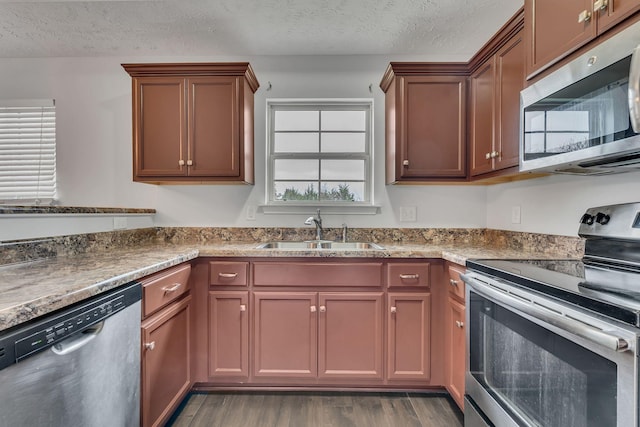 kitchen with a textured ceiling, dark hardwood / wood-style flooring, sink, and stainless steel appliances