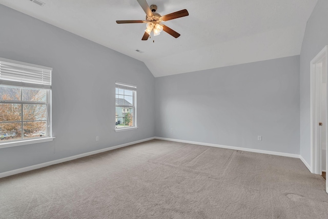 carpeted spare room with lofted ceiling, ceiling fan, and a healthy amount of sunlight