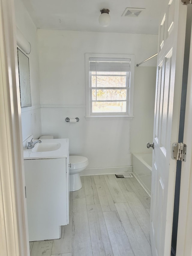 full bathroom with bathing tub / shower combination, hardwood / wood-style floors, vanity, and toilet