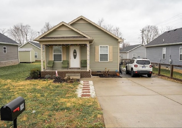 bungalow-style house featuring covered porch, concrete driveway, crawl space, fence, and a front lawn