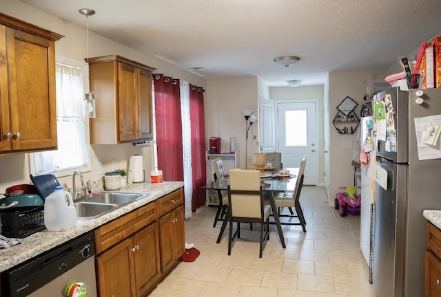 kitchen featuring light stone countertops, pendant lighting, stainless steel appliances, and sink