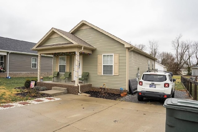 bungalow-style home with a porch and fence