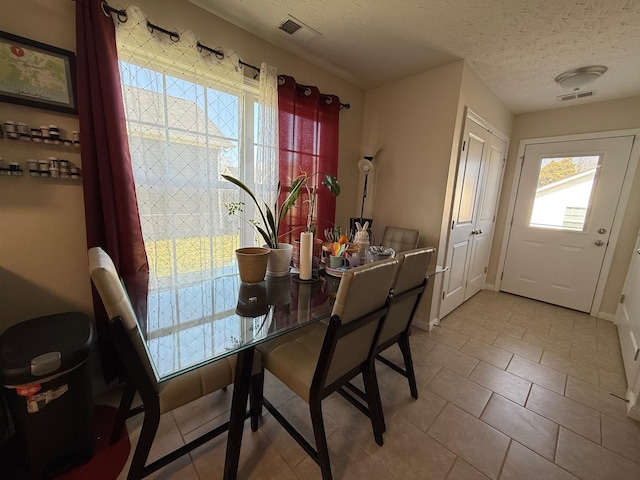 dining room featuring a textured ceiling, tile patterned floors, visible vents, and baseboards