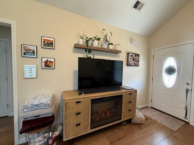 foyer entrance featuring lofted ceiling, visible vents, baseboards, and wood finished floors
