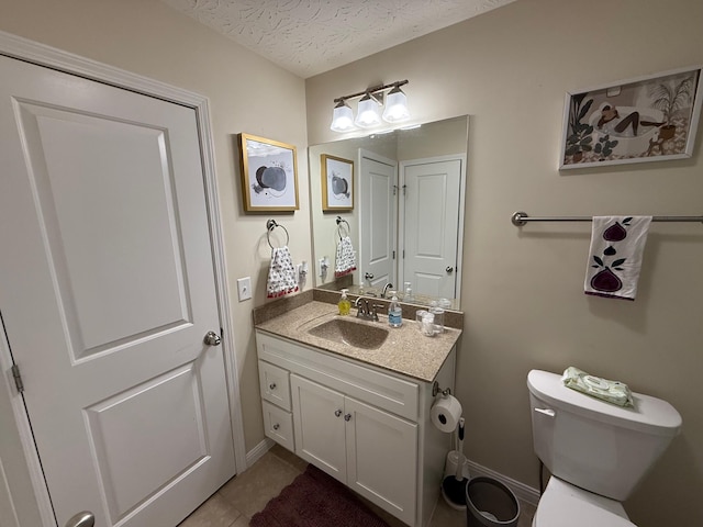 half bath with a textured ceiling, toilet, vanity, baseboards, and tile patterned floors