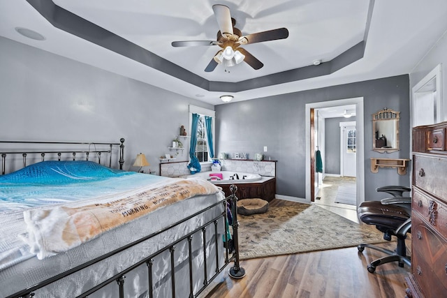 bedroom featuring a raised ceiling, ceiling fan, and light hardwood / wood-style floors