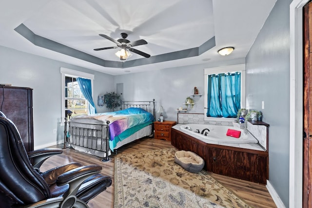 bedroom featuring ceiling fan, light hardwood / wood-style floors, and a raised ceiling