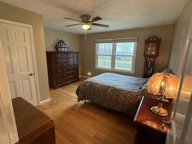 bedroom featuring ceiling fan, light wood-type flooring, and a textured ceiling