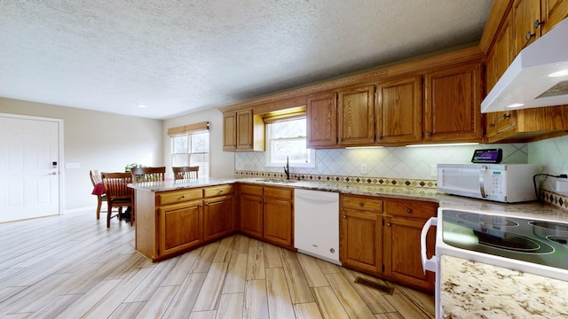 kitchen featuring sink, a textured ceiling, white appliances, light hardwood / wood-style flooring, and kitchen peninsula