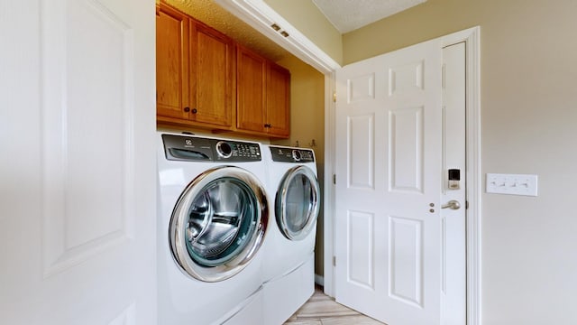 laundry room with a textured ceiling, cabinets, and washer and clothes dryer