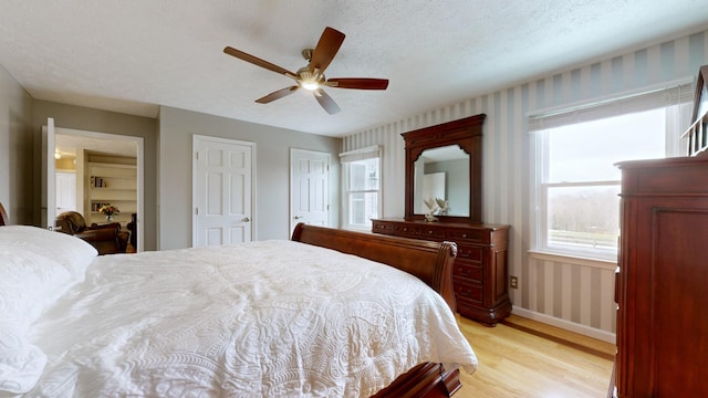 bedroom with light wood-type flooring, a textured ceiling, and ceiling fan