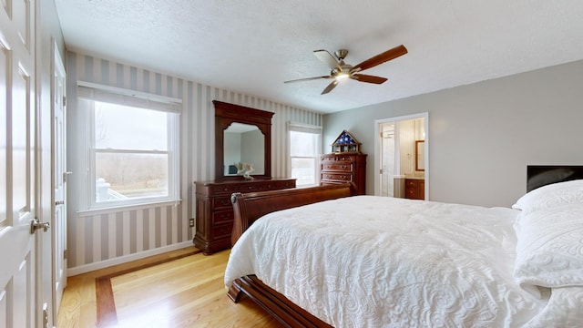 bedroom with ensuite bath, a textured ceiling, ceiling fan, and light hardwood / wood-style flooring