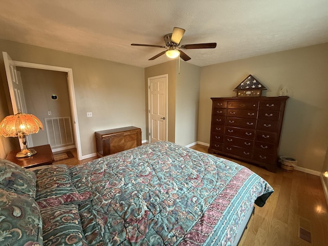 bedroom featuring ceiling fan, hardwood / wood-style floors, and a textured ceiling