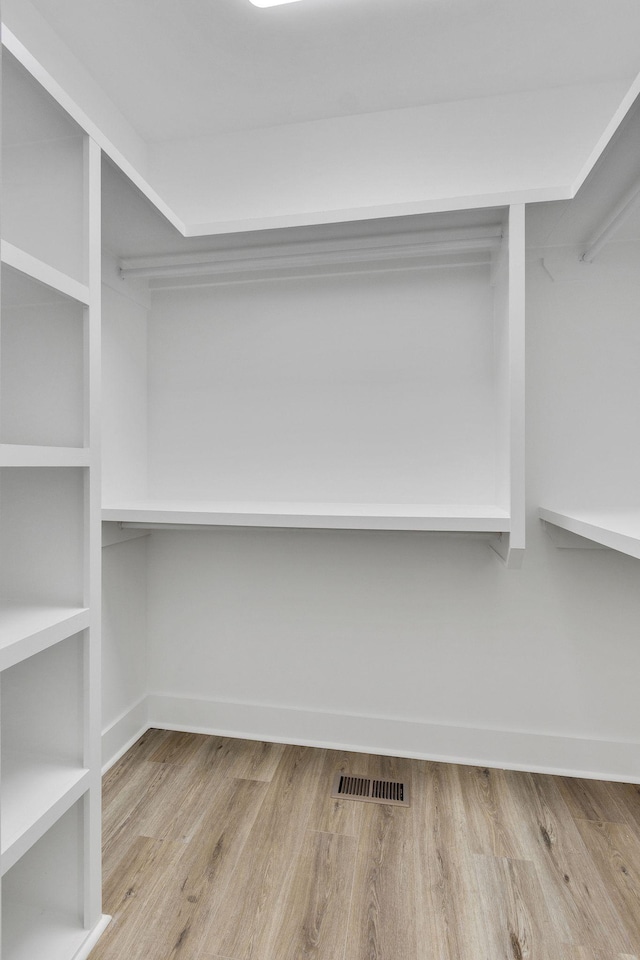 walk in closet with light hardwood / wood-style flooring