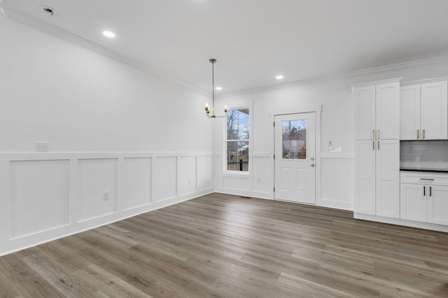 unfurnished dining area featuring light hardwood / wood-style floors and ornamental molding