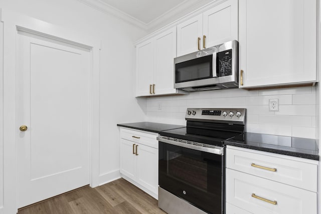 kitchen with white cabinets, crown molding, decorative backsplash, appliances with stainless steel finishes, and wood-type flooring