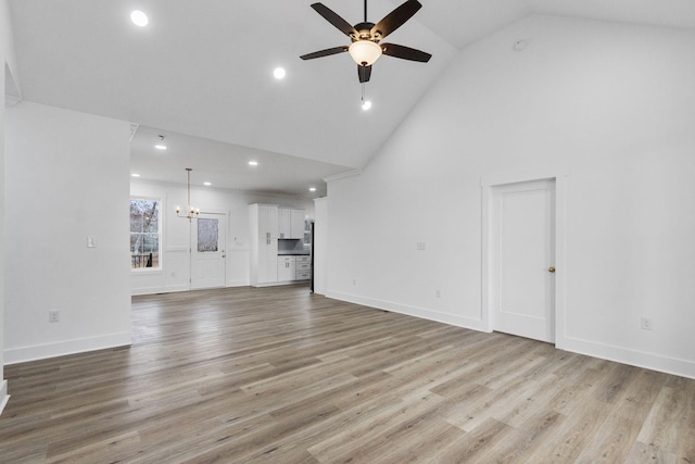 unfurnished living room featuring light hardwood / wood-style flooring, high vaulted ceiling, and ceiling fan with notable chandelier