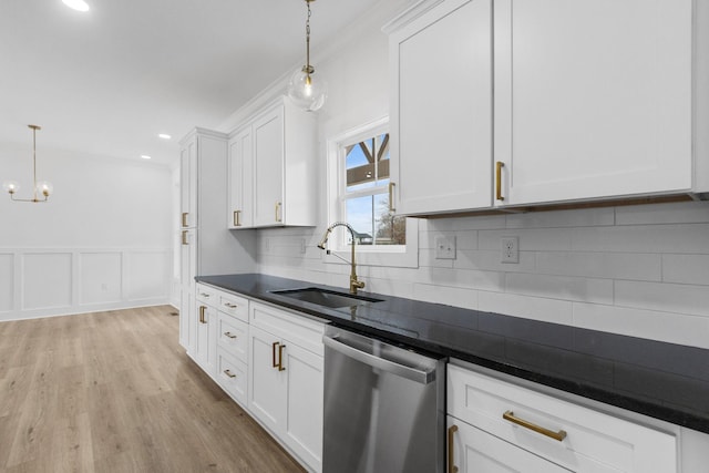 kitchen featuring stainless steel dishwasher, white cabinets, sink, and hanging light fixtures