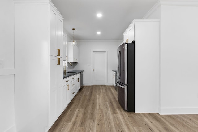 kitchen featuring white cabinetry, sink, hanging light fixtures, stainless steel appliances, and light wood-type flooring