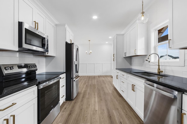 kitchen with appliances with stainless steel finishes, decorative light fixtures, white cabinetry, and sink