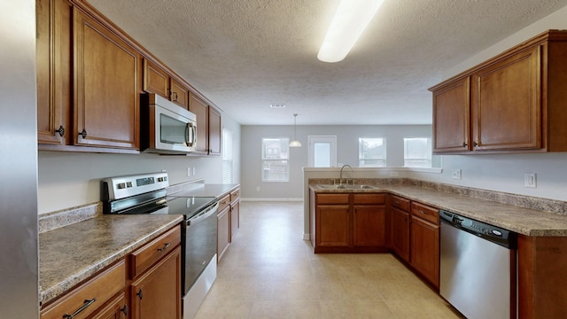 kitchen with a textured ceiling, sink, decorative light fixtures, and appliances with stainless steel finishes