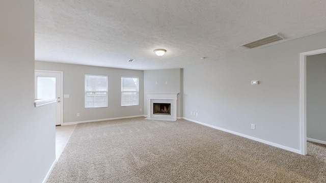 unfurnished living room with light colored carpet and a textured ceiling