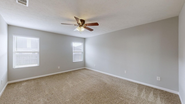 carpeted spare room featuring a textured ceiling, ceiling fan, and a healthy amount of sunlight