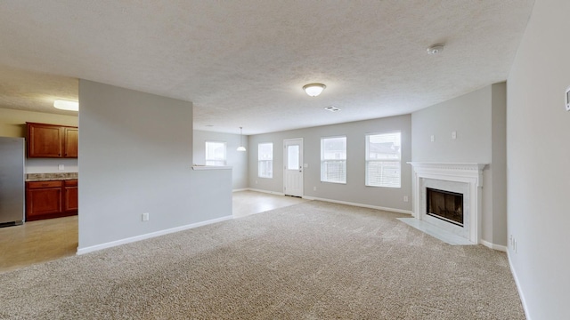 unfurnished living room featuring a textured ceiling and light colored carpet