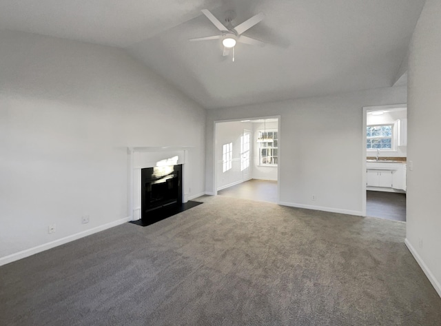 unfurnished living room with a wealth of natural light, ceiling fan, dark carpet, and vaulted ceiling