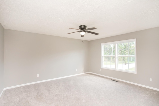 carpeted spare room featuring ceiling fan and a textured ceiling