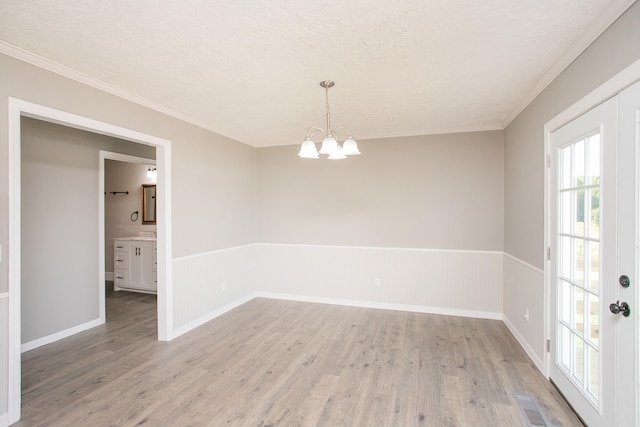 unfurnished room featuring a textured ceiling, a notable chandelier, wood-type flooring, and crown molding