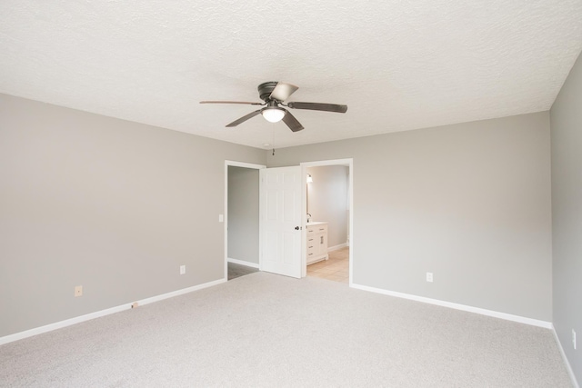 interior space featuring ceiling fan, light colored carpet, a textured ceiling, and connected bathroom