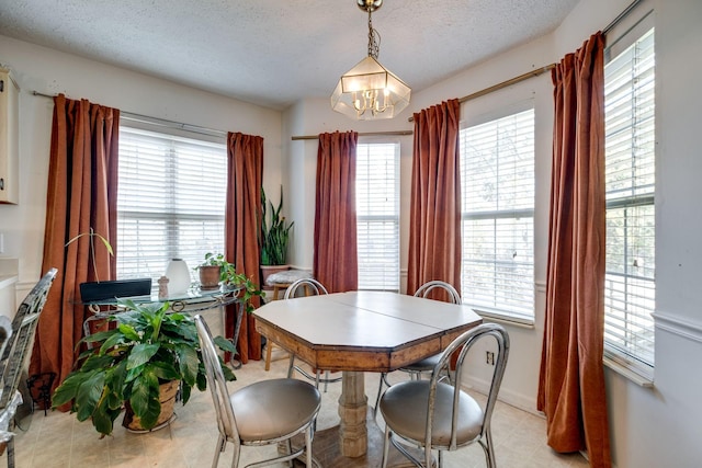 dining area featuring a textured ceiling, plenty of natural light, and a notable chandelier