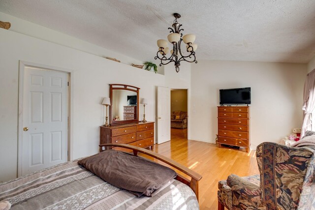 bedroom with hardwood / wood-style floors, a notable chandelier, a textured ceiling, and vaulted ceiling