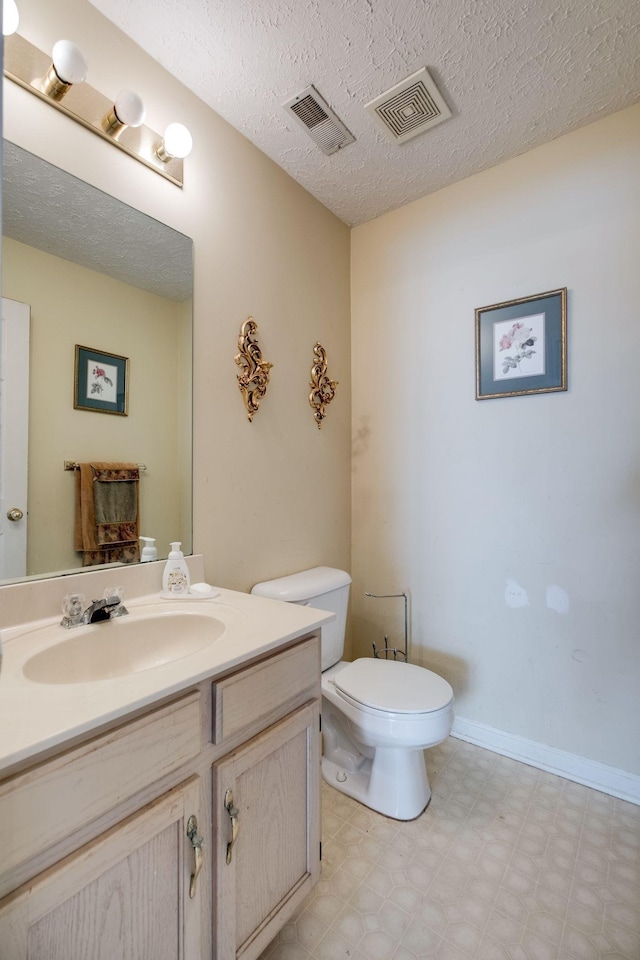 bathroom with vanity, a textured ceiling, and toilet