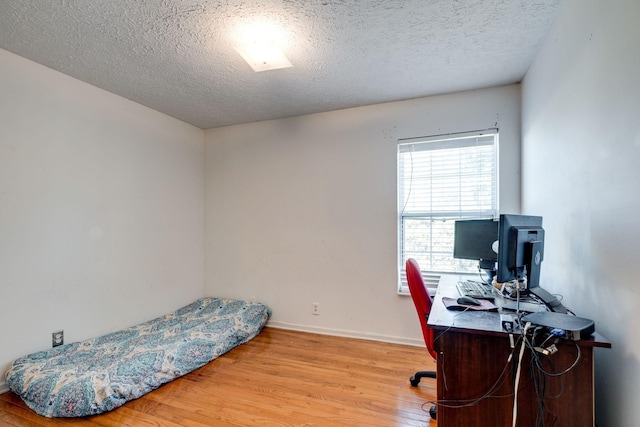 bedroom with a textured ceiling and light hardwood / wood-style flooring