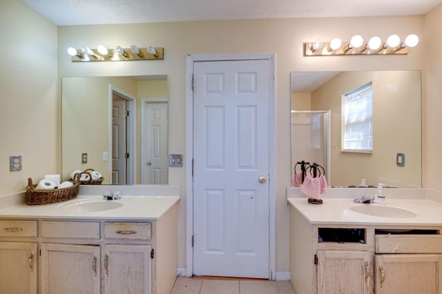 bathroom featuring tile patterned flooring, vanity, a textured ceiling, and walk in shower