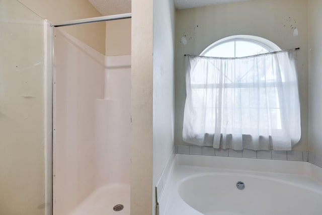 bathroom with a textured ceiling and independent shower and bath