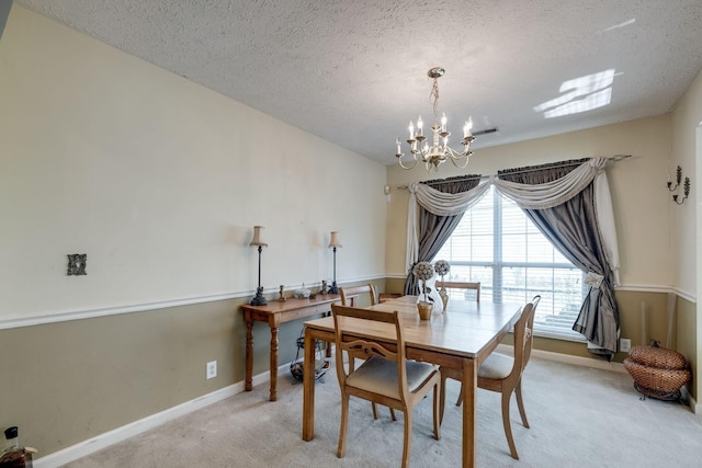 carpeted dining area featuring a textured ceiling and an inviting chandelier