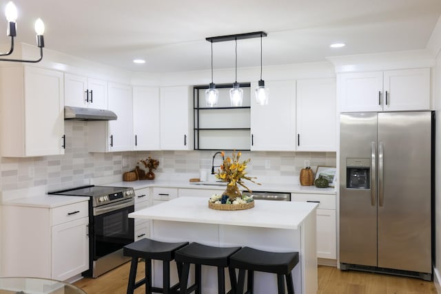 kitchen with white cabinets, light wood-type flooring, appliances with stainless steel finishes, and tasteful backsplash