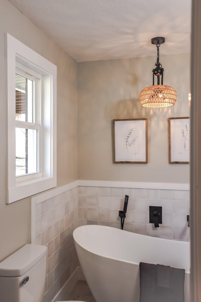 bathroom featuring a tub, tile walls, and toilet