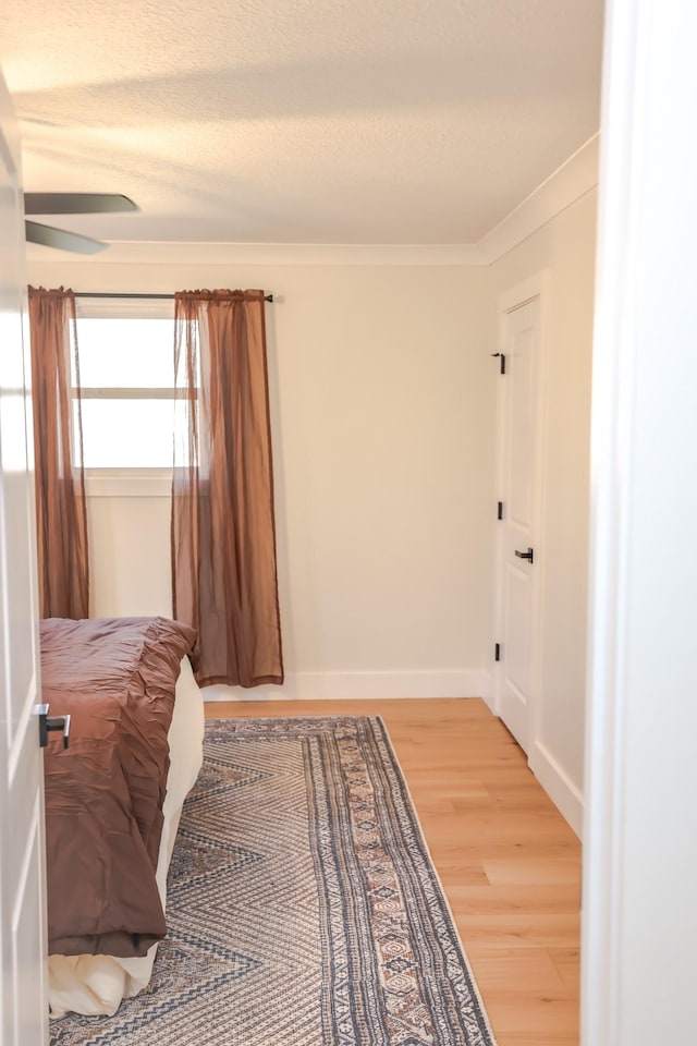 bedroom featuring a textured ceiling, hardwood / wood-style flooring, and crown molding