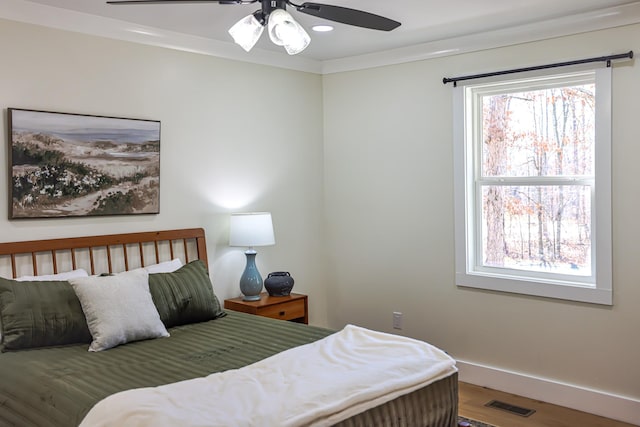 bedroom with hardwood / wood-style flooring, ceiling fan, and ornamental molding