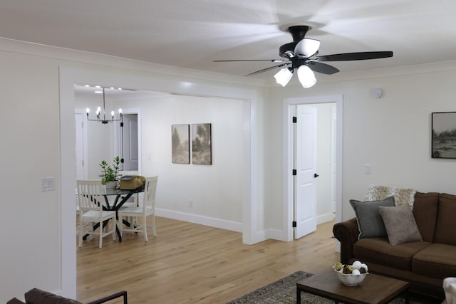 living room with ceiling fan with notable chandelier, light wood-type flooring, and crown molding