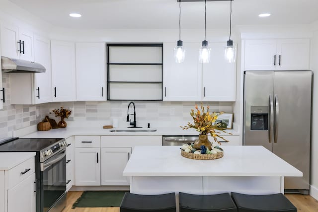 kitchen with appliances with stainless steel finishes, light wood-type flooring, sink, white cabinetry, and hanging light fixtures