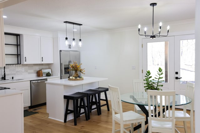 kitchen with sink, a center island, light hardwood / wood-style flooring, white cabinets, and appliances with stainless steel finishes