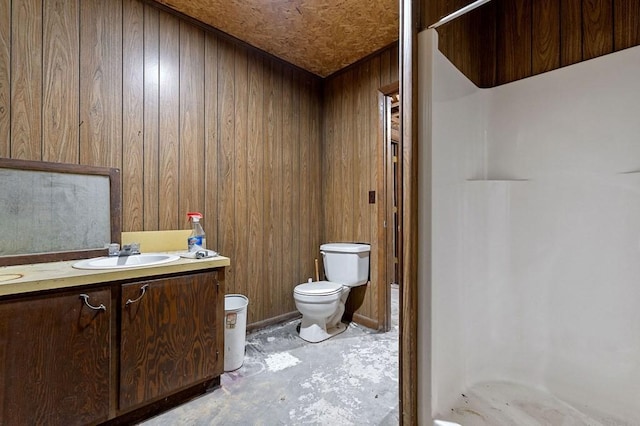 bathroom featuring a shower, wood walls, concrete floors, toilet, and vanity