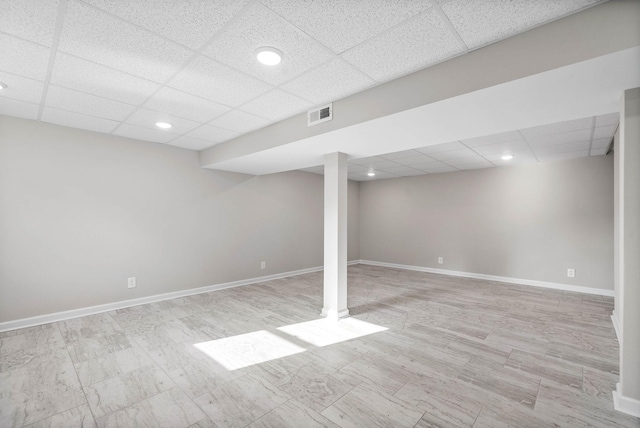 basement with a drop ceiling and light hardwood / wood-style flooring